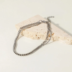 Double-layered silver Cuban and snake chain bracelet for men on a stone pedestal