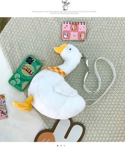 Detail of cute white plush goose crossbody bag with yellow scarf on knit background
