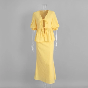 Detail of yellow V-neck crop top with bow tie and high-waisted fishtail maxi skirt