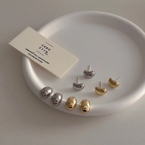 Minimalist gold and silver pebble studs displayed on a premium white ceramic tray