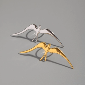 Detailed view of bird-shaped open rings in gold and silver finish with metallic shine