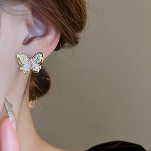 Gros plan de boucles d'oreilles papillon dorées avec zircon montrant la texture du métal
