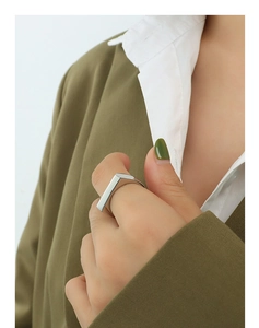 Detail shot of a polished silver rectangular geometric ring on a model hand