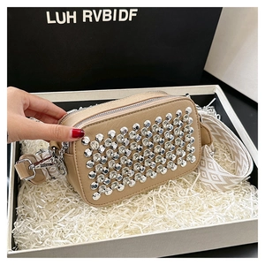 Close-up of a studded small square crossbody bag with a wide jacquard shoulder strap