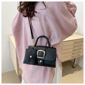 Detail of black leather square bag with gold horseshoe buckle and coin purse attachment