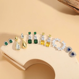 Elegant emerald and zircon drop earrings collection on geometric display stands