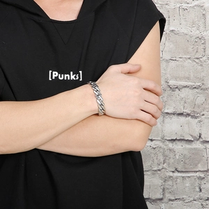 Detail of a punk style silver stainless steel Cuban chain bracelet on a male wrist