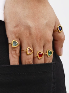 Detail van vijf gouden ringen met gefacetteerde driehoekige glasstenen in diverse kleuren