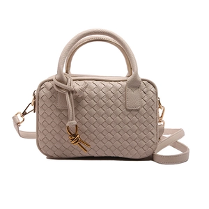 Chic beige hand-woven Boston pillow bag with knotted top handle and golden hardware