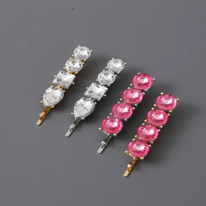 Detailed view of hairpins with round, square, and teardrop rhinestones on a grey backdrop