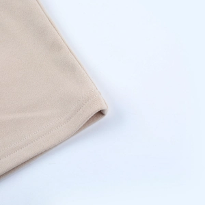 Close-up of high-density double-needle stitching on the hem of a beige knitted dress