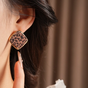 Détail d'une boucle d'oreille losange géométrique avec motif léopard et cadre doré