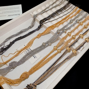 Detail of layered snake chains in gold, silver, and black finish on a jewelry tray