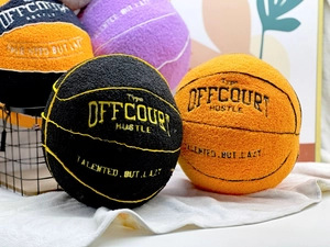 Close-up of soft plush basketball pillows in black and orange with detailed embroidery