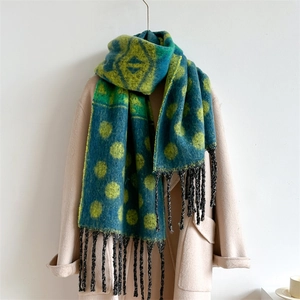 Close-up of a teal and yellow polka dot patterned scarf with dark fringe on a beige coat