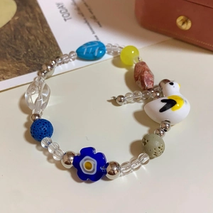 Detail of colorful handmade beaded bracelet featuring a white duck pendant and blue flower