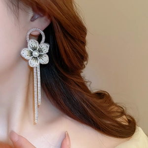 Vue latérale de boucles d'oreilles à longs glands avec fleurs brodées et strass brillants
