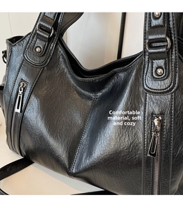 Detailed macro of vintage black tote bag featuring textured leather and silver rivets