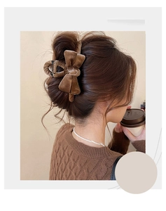 Detail of a large brown velvet bow hair claw clip worn on hair with a luxury texture