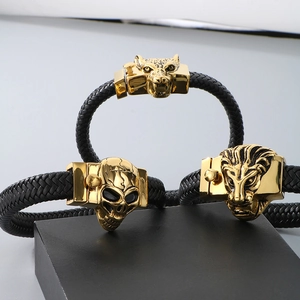 Close-up of wolf and skull braided leather bracelets with gold-tone stainless steel charms