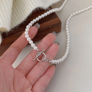 French style 925 sterling silver OT buckle pearl necklace held by hand on wood