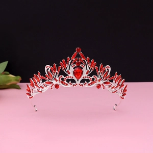 Detailed close-up of baroque silver crown with red crystals and teardrop main stone