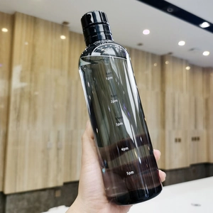 Transparent plastic water bottle with time markers and black lid held by a hand