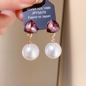Close-up of 925 silver needle earrings with purple crystal and white pearl detail