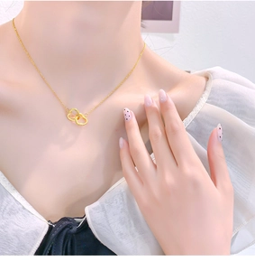 Close-up of interlocking heart necklace in 18k gold plating on a woman's collarbone