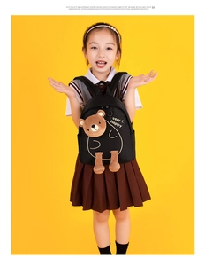 Detail of cute brown plush bear ornament and happy print on black school backpack
