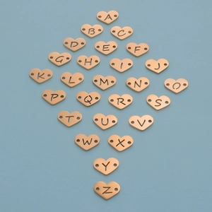 Golden 12mm stainless steel heart alphabet charms set on blue background