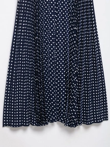Detailed close-up of navy blue polka dot pleated hem on a flowy midi dress