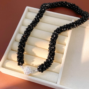 Close-up of black faceted beads and spherical diamond-set magnetic clasp on the necklace