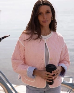 Detail of pink quilted jacket showing contrast white piping and blue striped sleeve lining