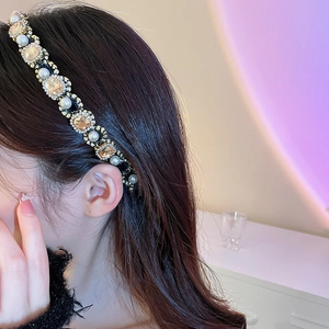 Detail of elegant headband featuring amber crystals and white pearls on a black frame