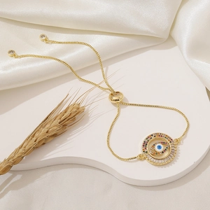 Gold evil eye bracelet with cubic zirconia and adjustable chain on white tray