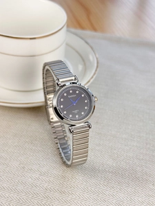 Detail of quartz watch featuring dark grey dial, diamond markers, and blue needles