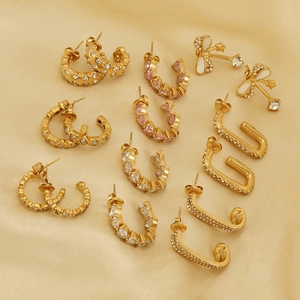 Détail de boucles d'oreilles dorées avec cristaux sur fond en satin de champagne