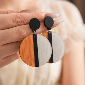 Détail de boucles d'oreilles rondes en acrylique aux motifs géométriques noirs et marrons