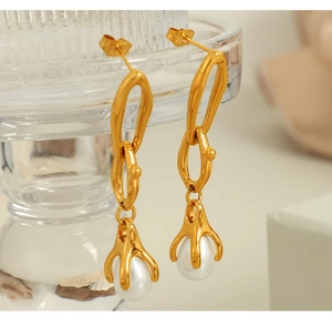 Macro detail of 18K gold chain earrings with elegant white teardrop pearl drop accents