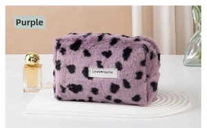 Detail of purple leopard plush makeup bag with Love Youth label on a textured base