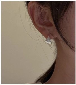Close-up of S925 sterling silver hoop earrings with textured shell pattern on a model