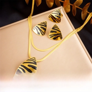 Macro shot of gold-plated jewelry set with black enamel stripes on triangle pendants