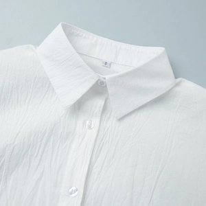 Detail of white lapel collar and pleated texture fabric with transparent buttons