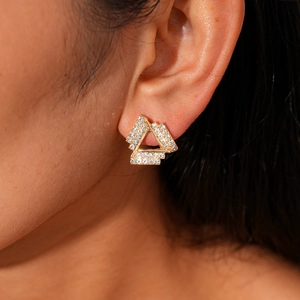 Close-up of a gold triangle earring set with sparkling rhinestones on an ear lobe