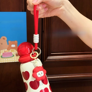 Detail of cute insulated mug with red heart pattern and ball lid with hand strap