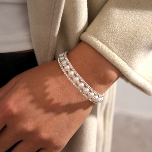 Close-up of three-row layered bracelet with white pearls and sparkling crystal rhinestones