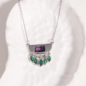 Close-up of hip hop pendant with purple gem and green stones on a white shell tray