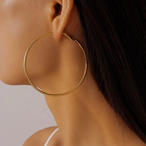 Close-up of a large gold minimalist geometric hoop earring worn by a model for a chic look