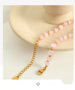 Close-up of pink cat eye stone beaded necklace with gold spacers and lobster clasp